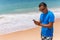 Man use phone on the beach typing or use internet on sunny day