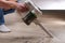 A man uses a bagless vertical cordless vacuum cleaner to clean floor