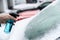 Man uses a bottle of de-icer to defrost the ice-covered windshield