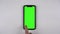 A man uses a phone with a green screen. The man's finger taps on the screen of the smartphone lying on the table