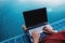 A man using computer laptop, at poolside with dipping legs in the water. Clipping path computer screen