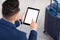 Man Using Digital Tablet With Blank Screen While Sitting With Luggage Outdoors