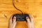 Man using game pad controller on wooden desk, top view