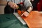 A man using a hammer and a punch makes holes for hand-stitching a leather product