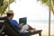 A man using his laptop and working from sea beach