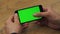 Man using horizontal smartphone with green screen. Close-up shot of man`s hands with mobile phone. Chroma key. Close up