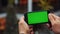 Man using horizontal smartphone with green screen. Close-up shot of man`s hands with mobile phone. Chroma key. Close up