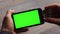 Man using horizontal smartphone with green screen. Close-up shot of man`s hands with mobile phone. Chroma key. Close up