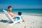 Man using laptop on deck chair at the beach