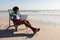 Man using laptop while relaxing in a beach chair on the beach