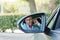 Man using mobile phone while driving car to work reflection in side mirror