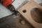 A man using powered drill with a hole saw bit to make precision hole in a wooden plank.