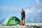 Man using radio near tent in mountains.