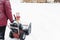 Man using red snowblower machine outdoor. Removing snow near house from yard
