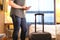 Man using smartphone in hotel room with baggage and suitcase.