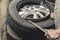 A man using a steel rod to assist in removing a tire from the rim. Using a tire bead breaker at a vulcanizing shop