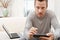 Man using tablet and computer on sofa at home.