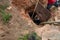 Man using a very long handled shovel to loosen septic sludge as tank is being pumped