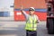 Man Using Walkie Talkie At Container Terminal, Industrial worker is controlling container loading