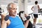 Man Using Weights Machine With Runner On Treadmill In Background