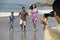 Man video recording happy Hispanic Latin family walking at beach