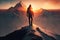 man, with view of the sun setting behind the mountain range, standing on snowy summit