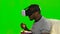 Man in a VR mask watching a movie and eating popcorn. Green screen