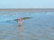 Man wading in shallow water with bucket of collected mussels fro