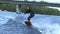 Man wakeboarding on river waves under city bridge in slow motion