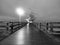 Man walk in autumn mist on wooden pier above sea. Depression, dark atmosphere.