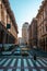 a man walking across a street next to many buildings and traffic in Genova