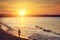 Man walking alone on the beach at sunset. Calm sea