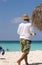 The man is walking along the beach Playa Paradise of the island of Cayo Largo, Cuba. Vertical. Copy space for text.