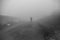 Man walking away on misty road. Man standing alone on rural foggy and misty asphalt road
