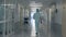 A man walking in a clinic hall. Person in doctor uniform walks in a hospital building.