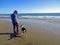 Man Walking Dog on Beach