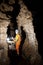 Man walking and exploring dark cave with light headlamp and map in his hand underground. Mysterious deep dark, explorer