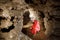 Man walking and exploring dark cave with light headlamp underground.