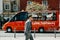 The man is walking in the foreground. A traditional tourist minibus rides down the city street in Lisbon in the