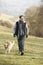 Man walking golden retriever in the country