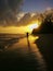 A man walking happily along the beach towards the blazing sunrise