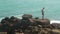 Man walking on a huge boulder on a beach