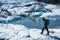 Man walking over white ice next to calm lake on the Matanuska Glacier in Alaska