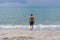 Man walking on the shore beach, sea in summer time. A charming man in shorts walking along the seashore. Waves and blue sea behind