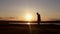 Man walking on summer meadow, sunset. Silhouette of the young man on the mountain top.