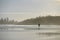 Man walking with surfboard through the mist, Long Beach, Pacific Rim National Park