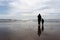 Man walking their child along a sun-drenched sandy beach