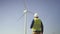 Man walking to wind mill and checking condition of mechanisms