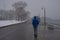 Man walking at Toronto waterfront Martin Goodman trail during heavy snowstorm, wet snow covering trees and branches.