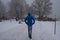 Man walking at Toronto waterfront Martin Goodman trail during heavy snowstorm, wet snow covering trees and branches.